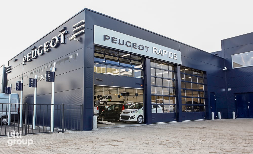 Glazed sectional overhead doors installed at a Peugeot service centre.