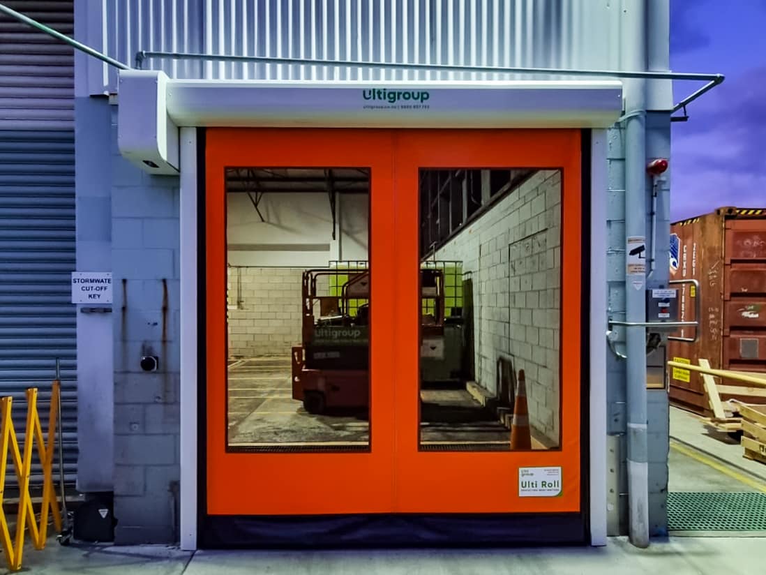 Orange Ulti Roll door with large vision panels installed at a warehouse entrance.