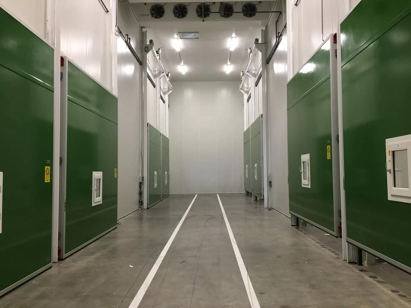 Green industrial sliding doors installed in a temperature-controlled facility corridor.