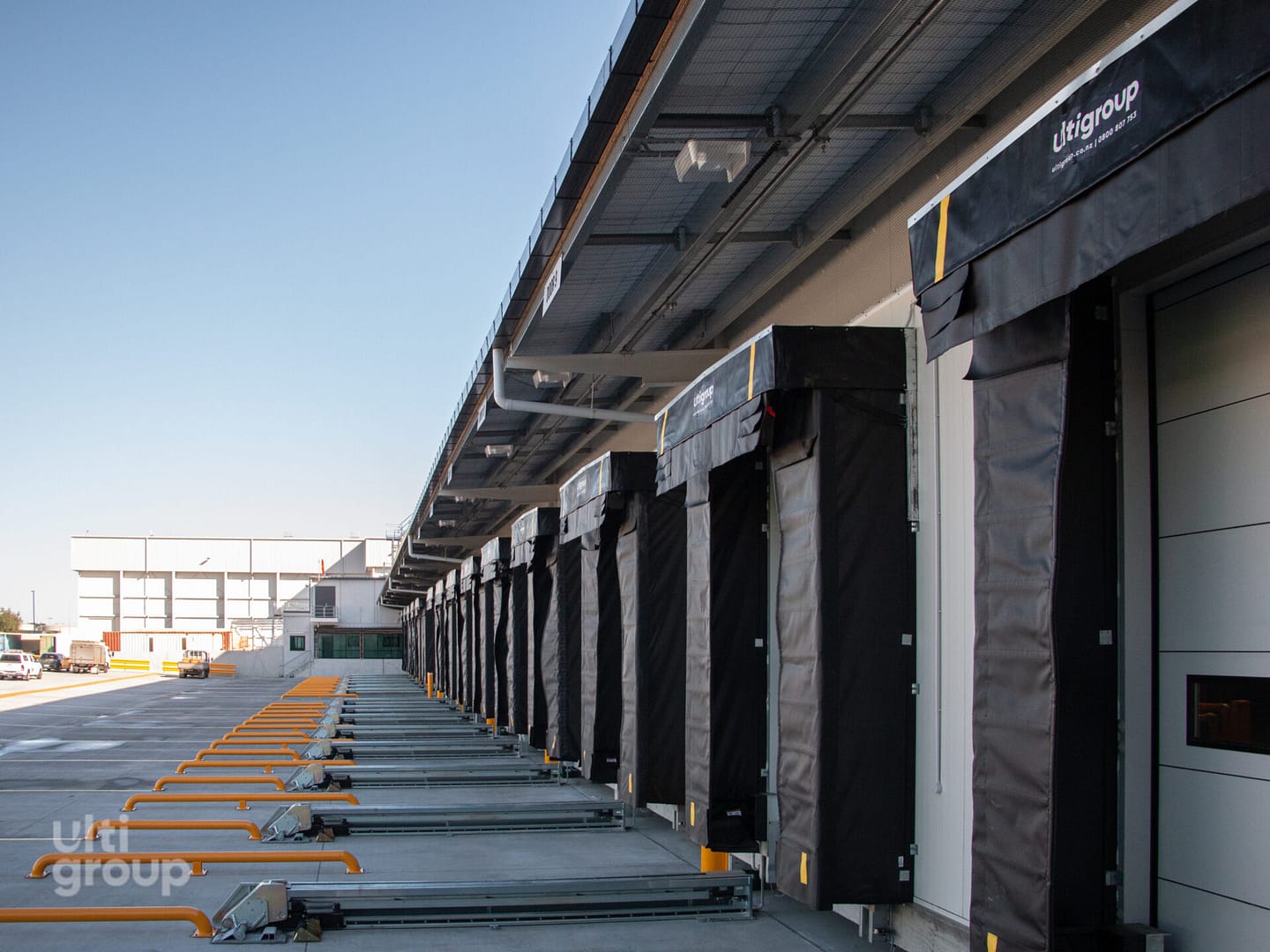Row of industrial loading docks with black dock seals and yellow wheel guides.