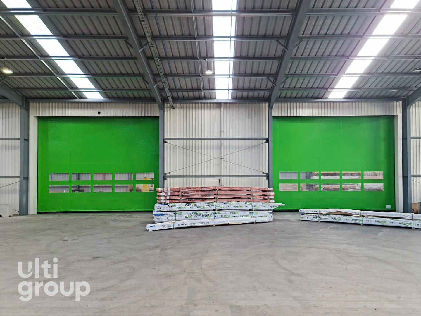 Two green Ulti EX5 Doors installed in a large warehouse facility.