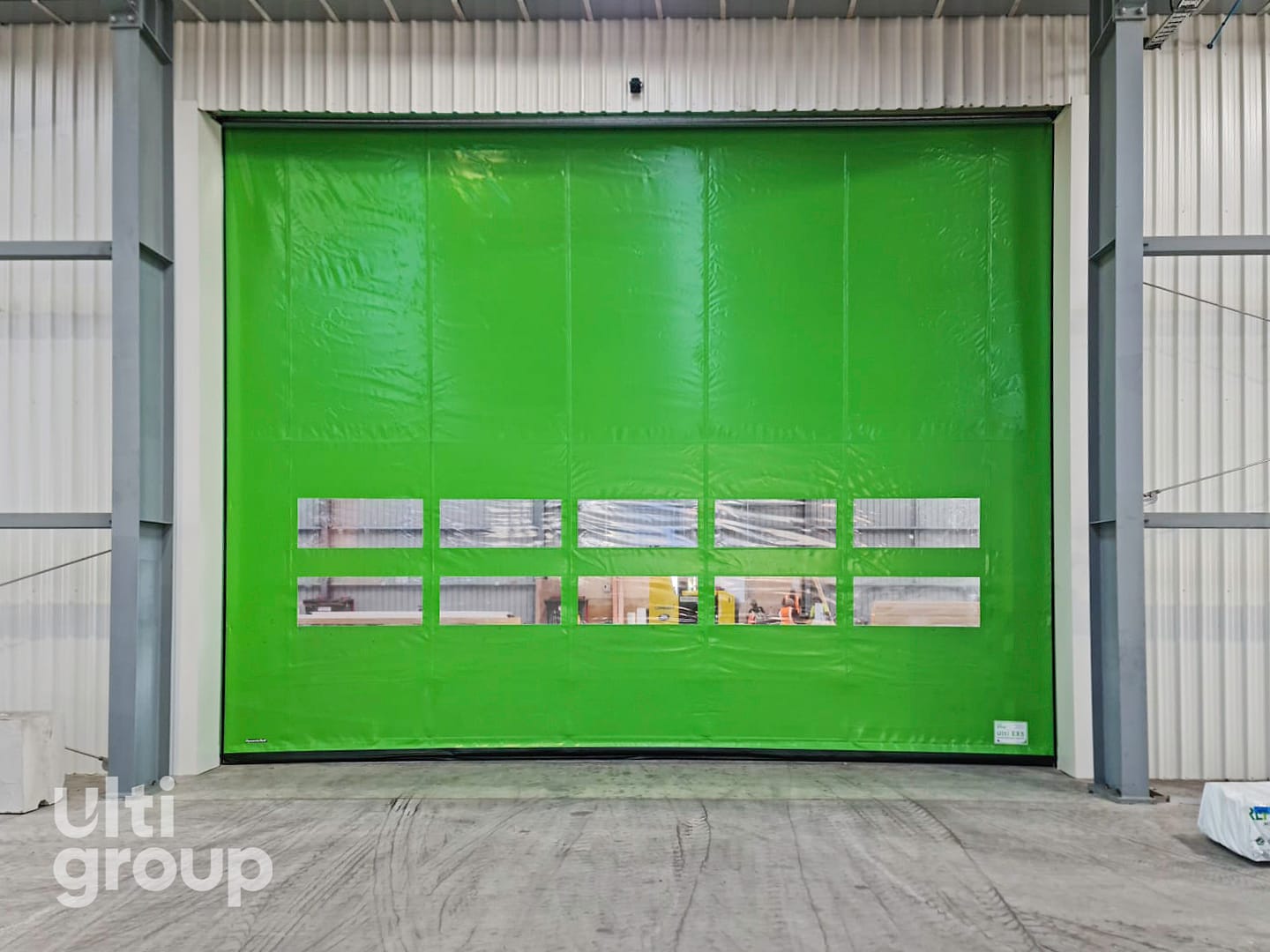 Green Ulti EX5 Door installed in a warehouse with vision panels.