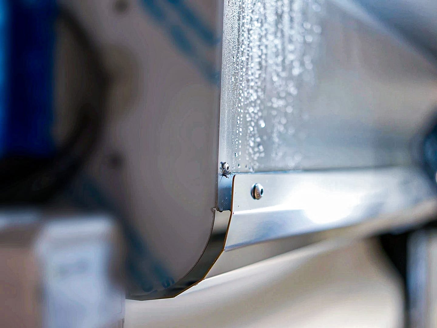 Close-up of condensation on a stainless steel industrial door hood.