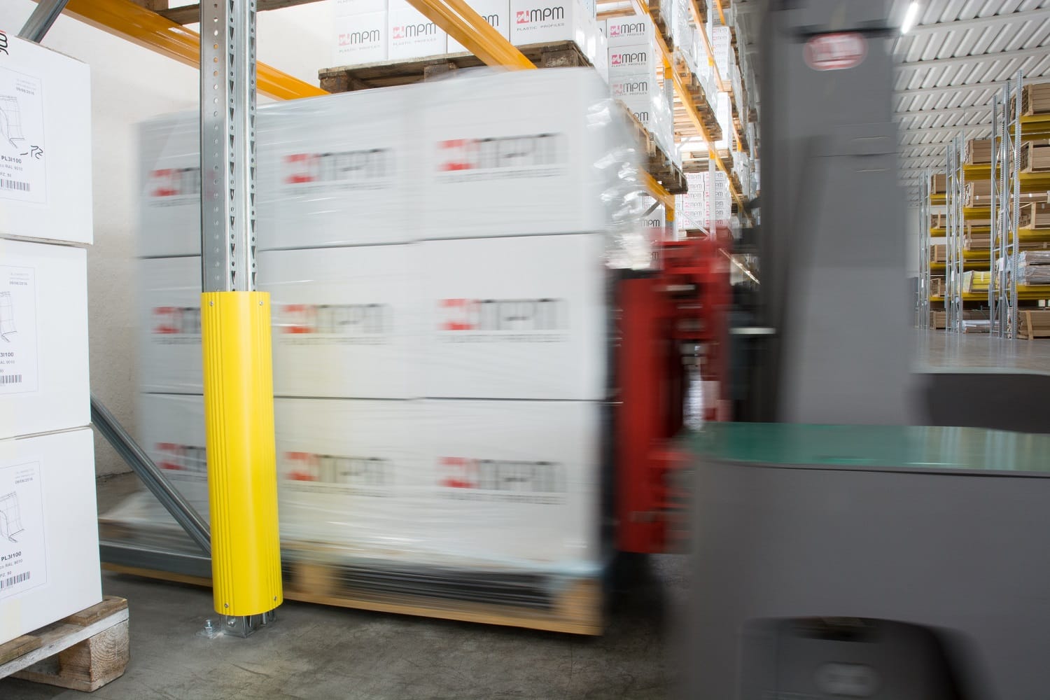 Yellow rack protector installed on a warehouse shelving upright.