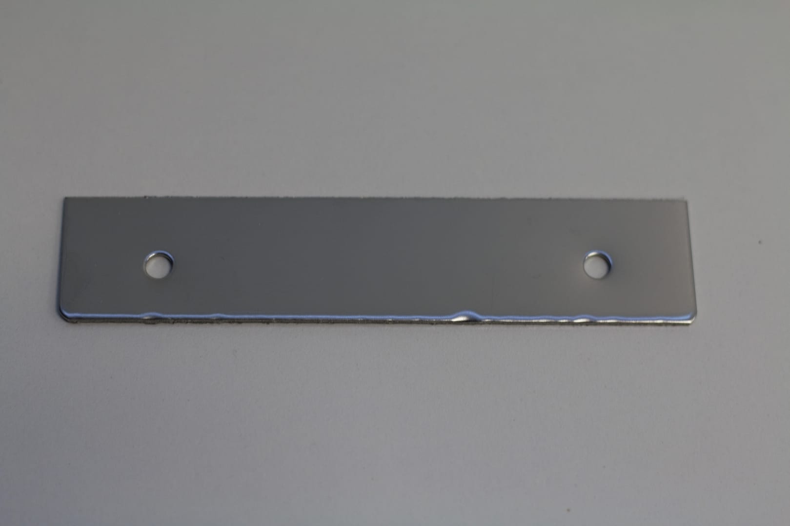 Rectangular stainless steel mounting plate with two pre-drilled holes.