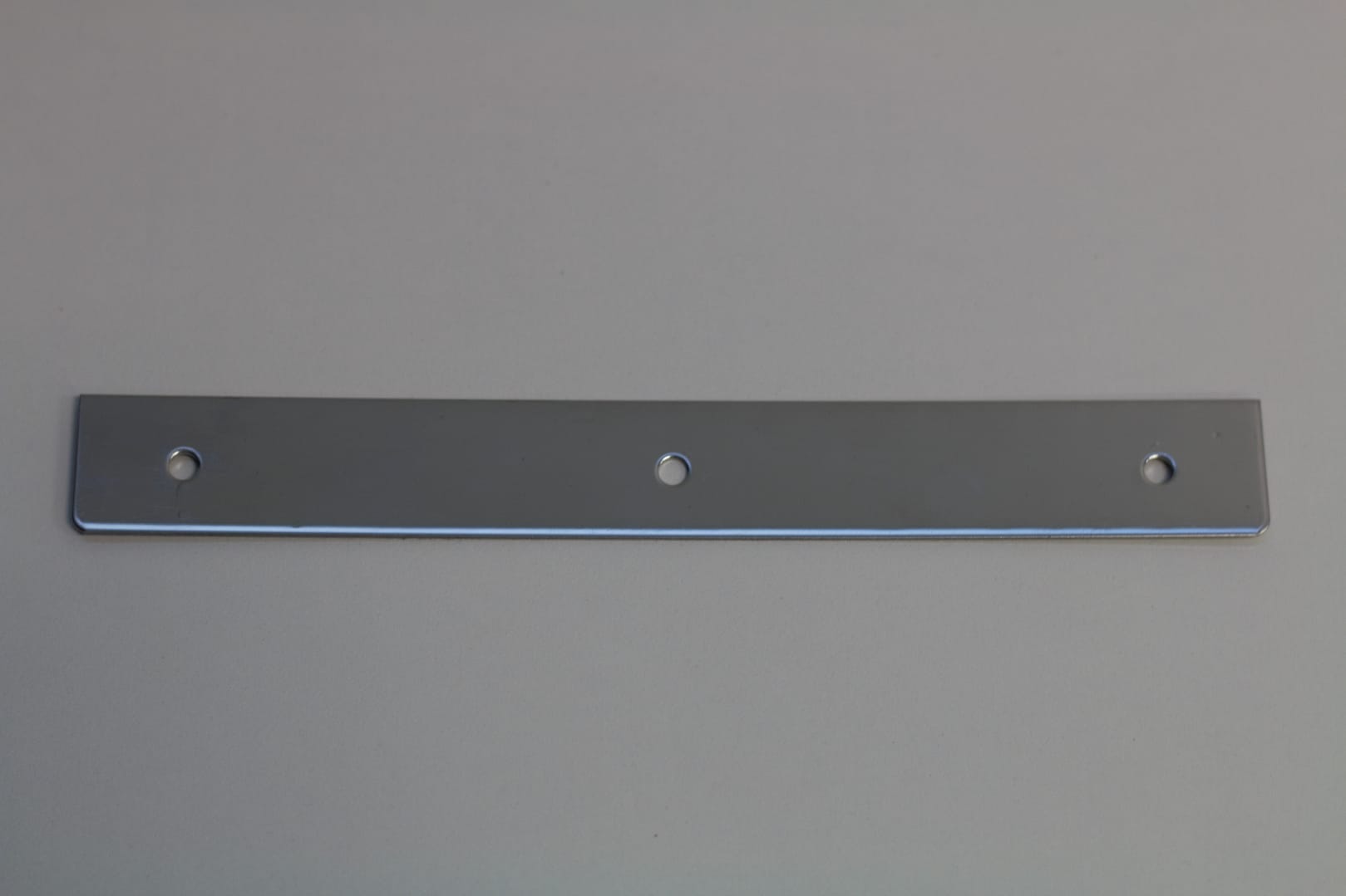 A flat rectangular metal mounting plate with three pre-drilled holes.