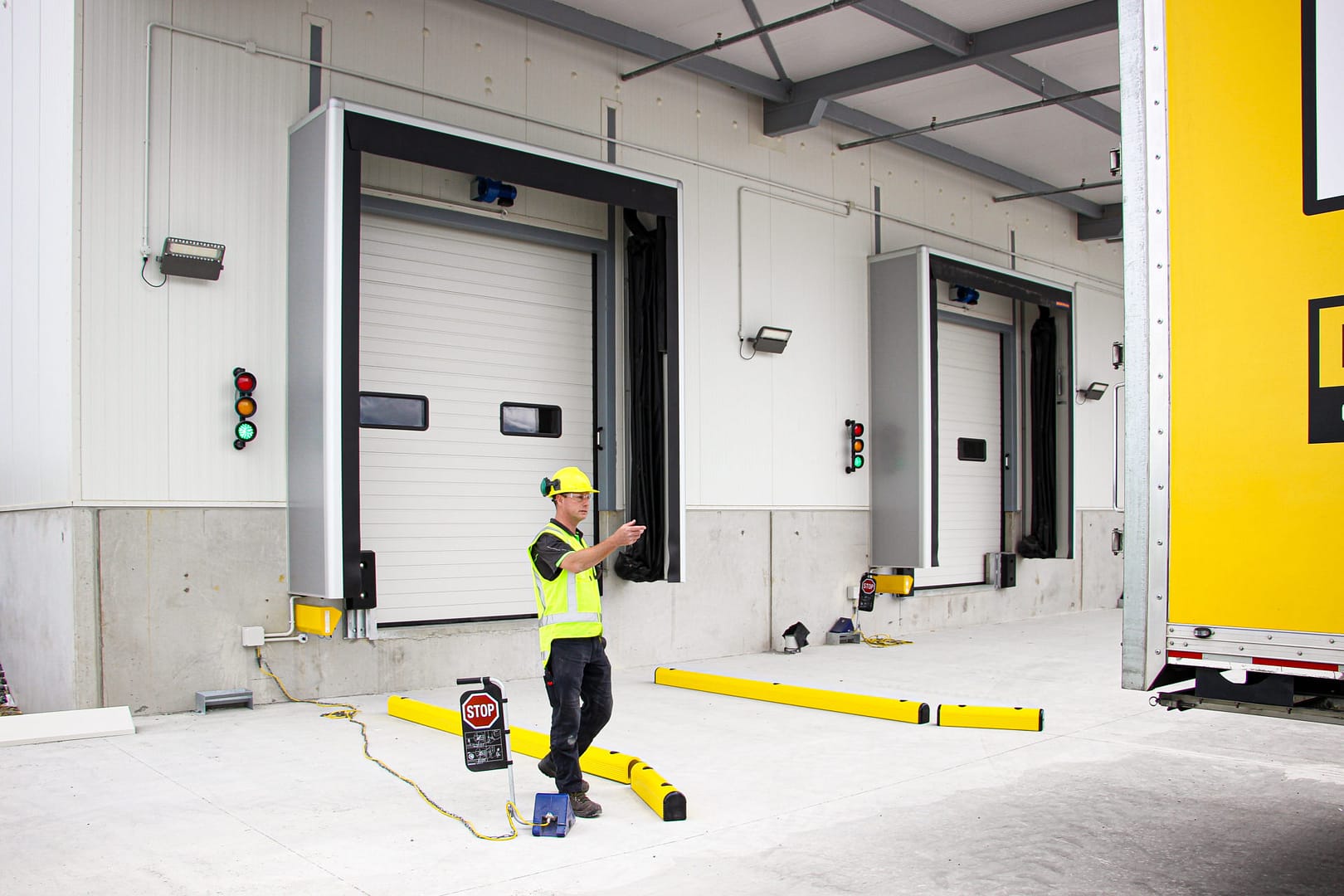 Worker directing a truck at a loading dock with insulated sectional doors.