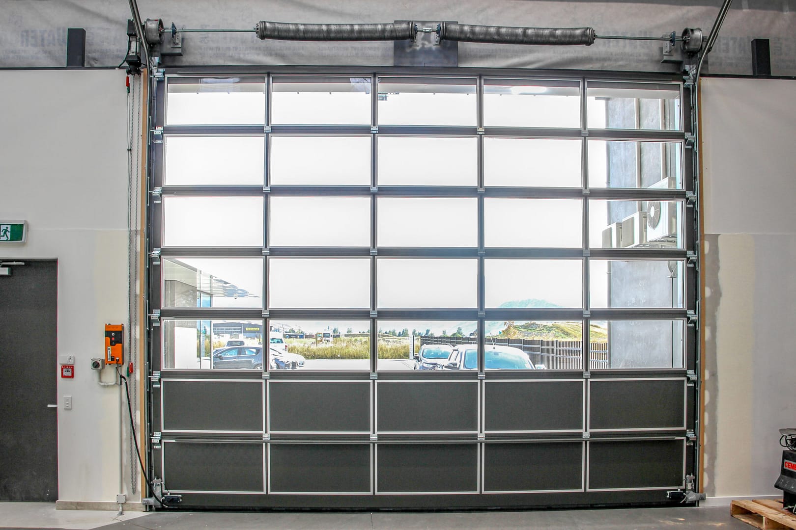 Internal view of a large glazed sectional door in a commercial workshop.