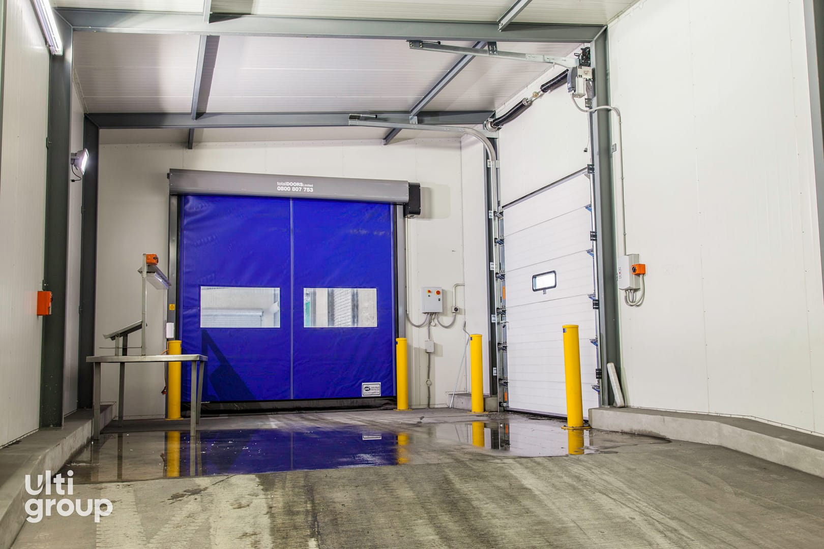 Blue high-speed roll door and white sectional door in a facility.