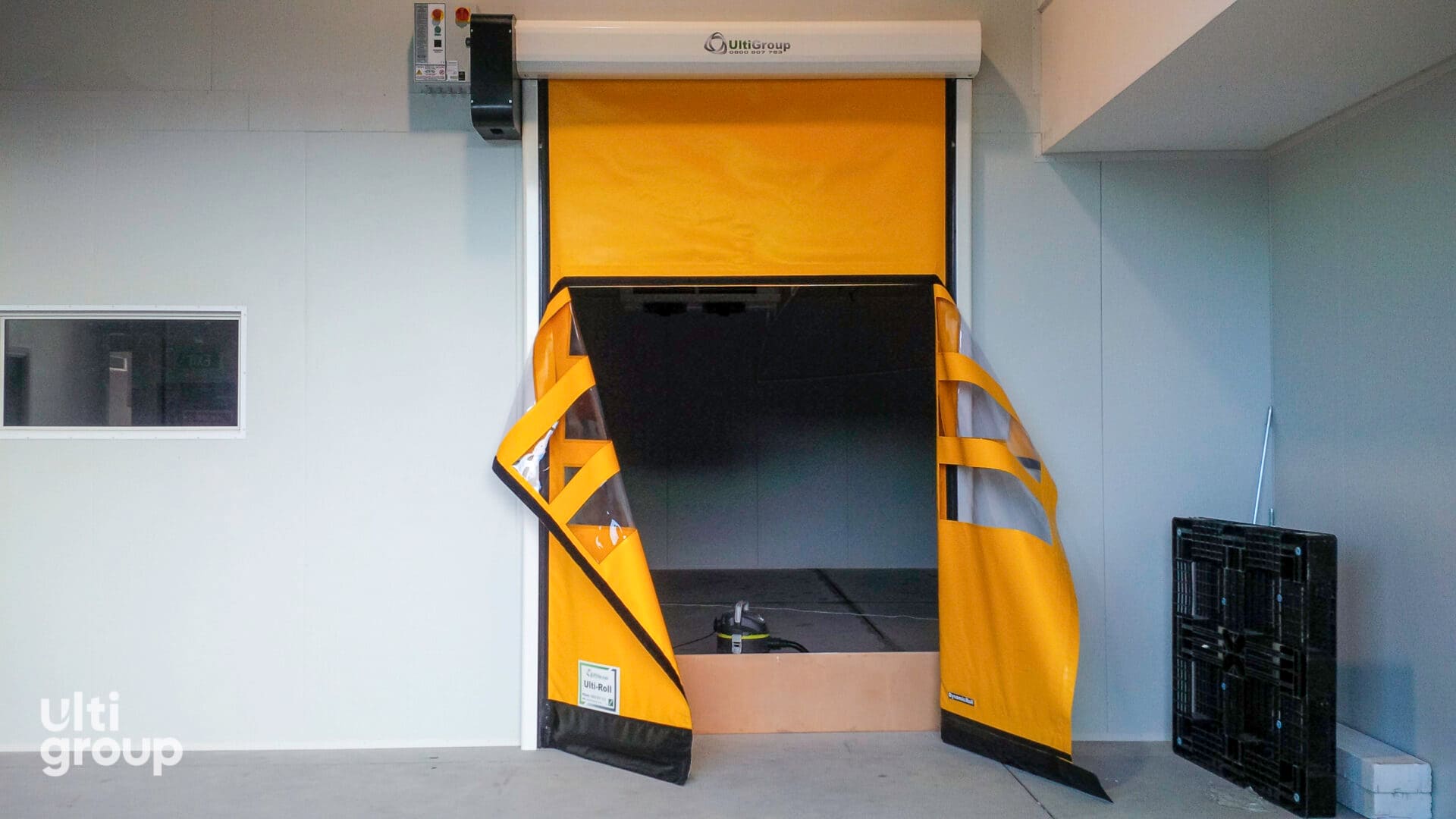Yellow Ulti-Roll door with T-cut opening for conveyor access.