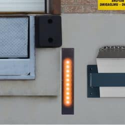 Orange LED dock guide light mounted on a concrete wall next to a dock bumper.