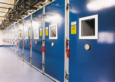 Row of blue insulated cold storage doors with viewing windows in a facility.
