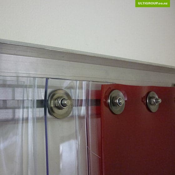 Close-up of face-mounted PVC strip curtains with stainless steel bolts and washers.