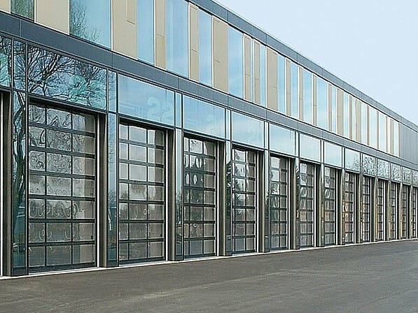 Row of glazed sectional industrial doors on a modern commercial building facade.