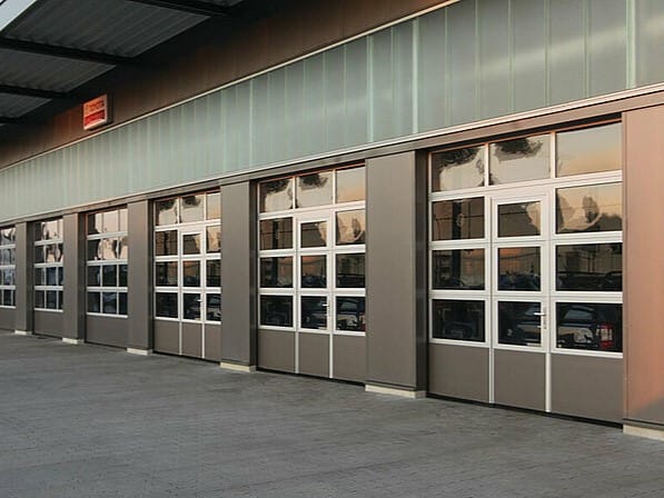 Series of glazed sectional industrial doors with integrated personnel access doors.