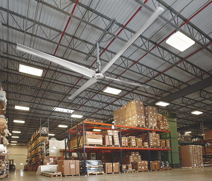 Large industrial ceiling fan installed in a warehouse above storage racking.