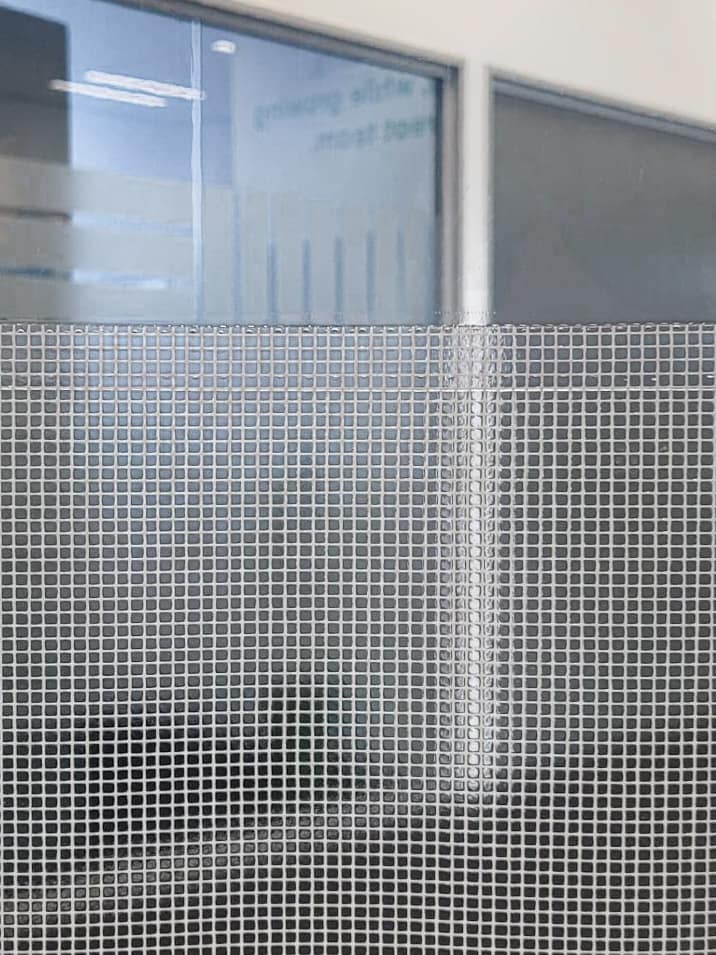 Close-up of a white mesh reinforced industrial door curtain material.