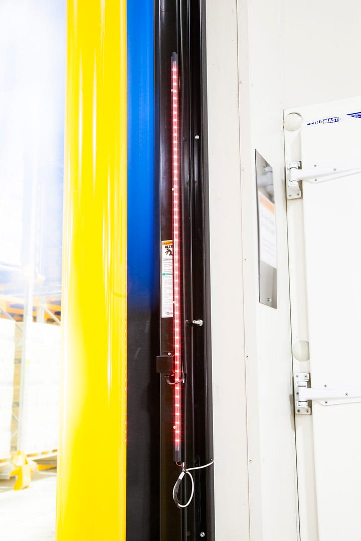 Red LED safety light strip installed on a black industrial door frame.