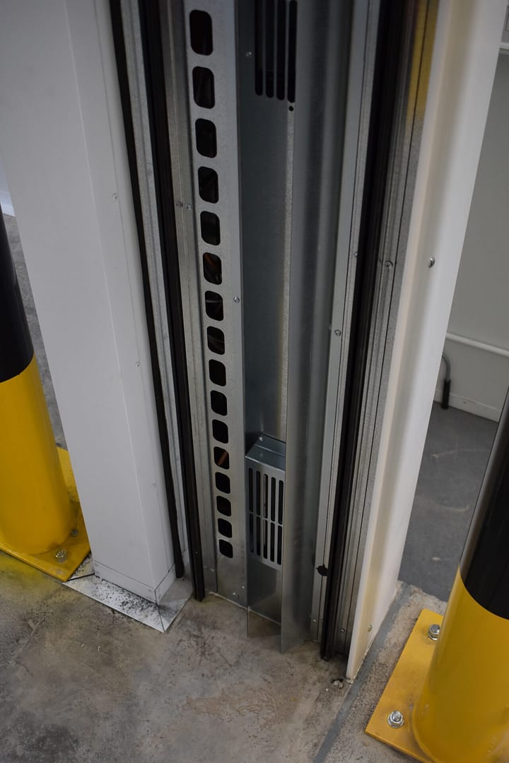 Close-up of a galvanised steel door track and safety bollards.