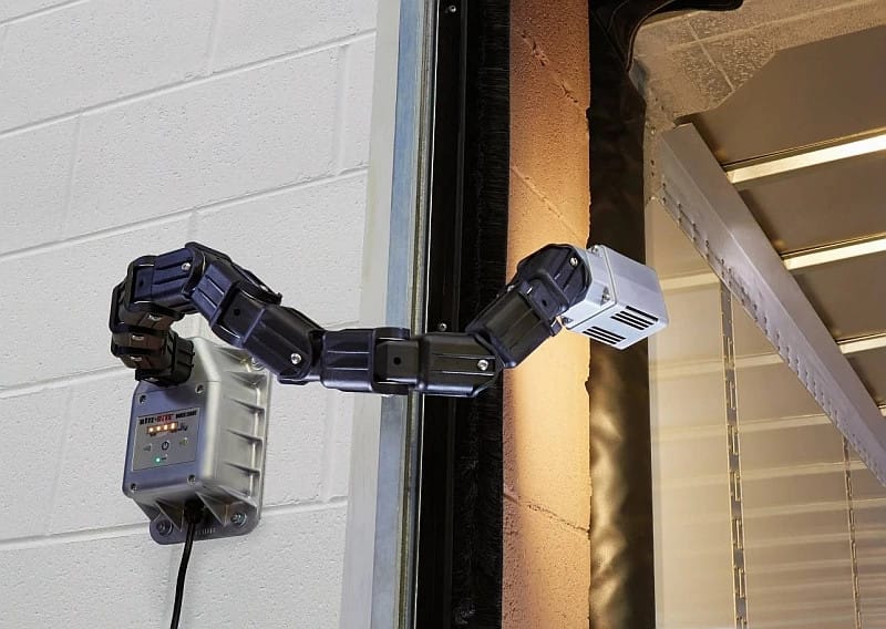 Adjustable black segmented dock light arm with LED head mounted to a white brick wall.