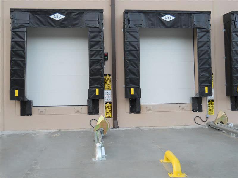 Manual wheel lock and dock bumpers at a loading bay with black dock seals.