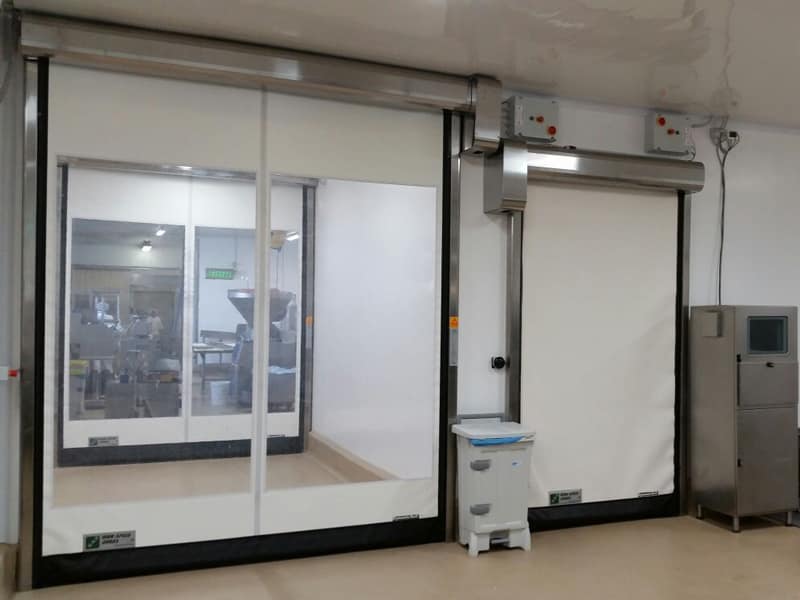 Two white rapid roll doors installed in a clean food processing facility.