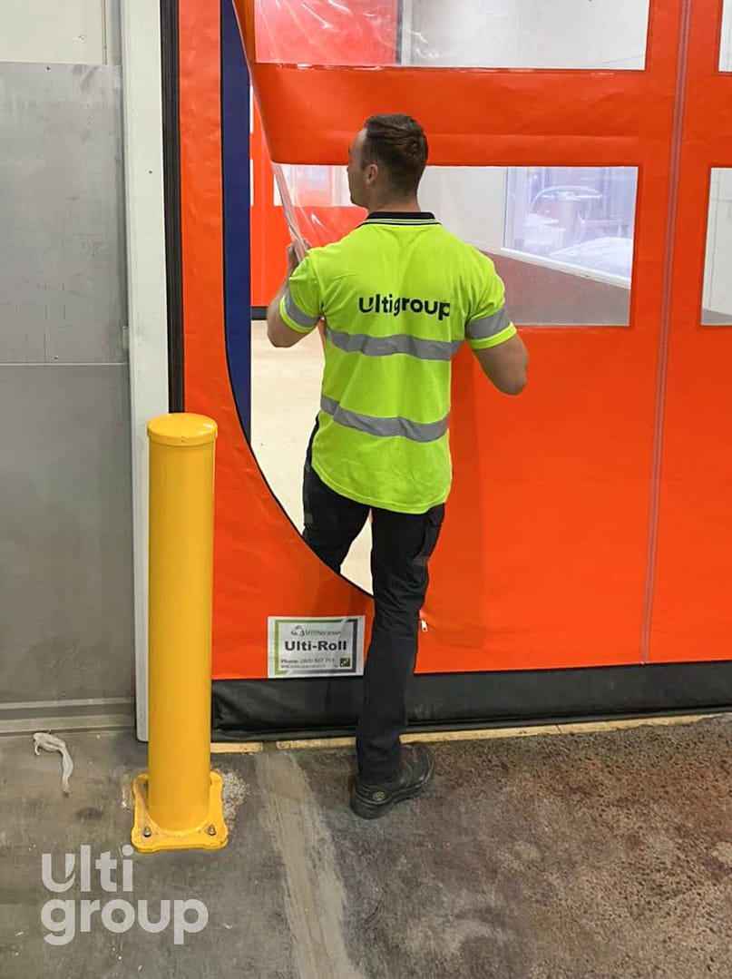 A worker demonstrating the escape zip feature on an orange Ulti-Roll door.