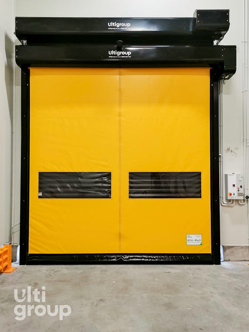 Yellow Ulti Komby Door with vision panels installed in a warehouse facility.