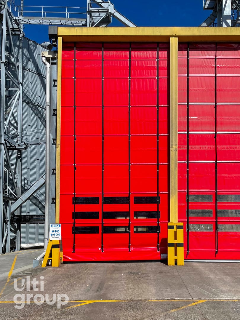 Large red Ulti Fold Door installed at an industrial facility.