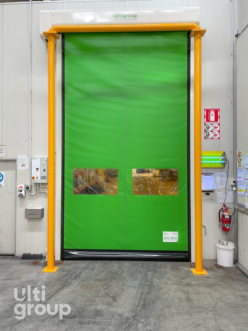 Green Ulti Roll high speed door with vision panels and yellow bollards.
