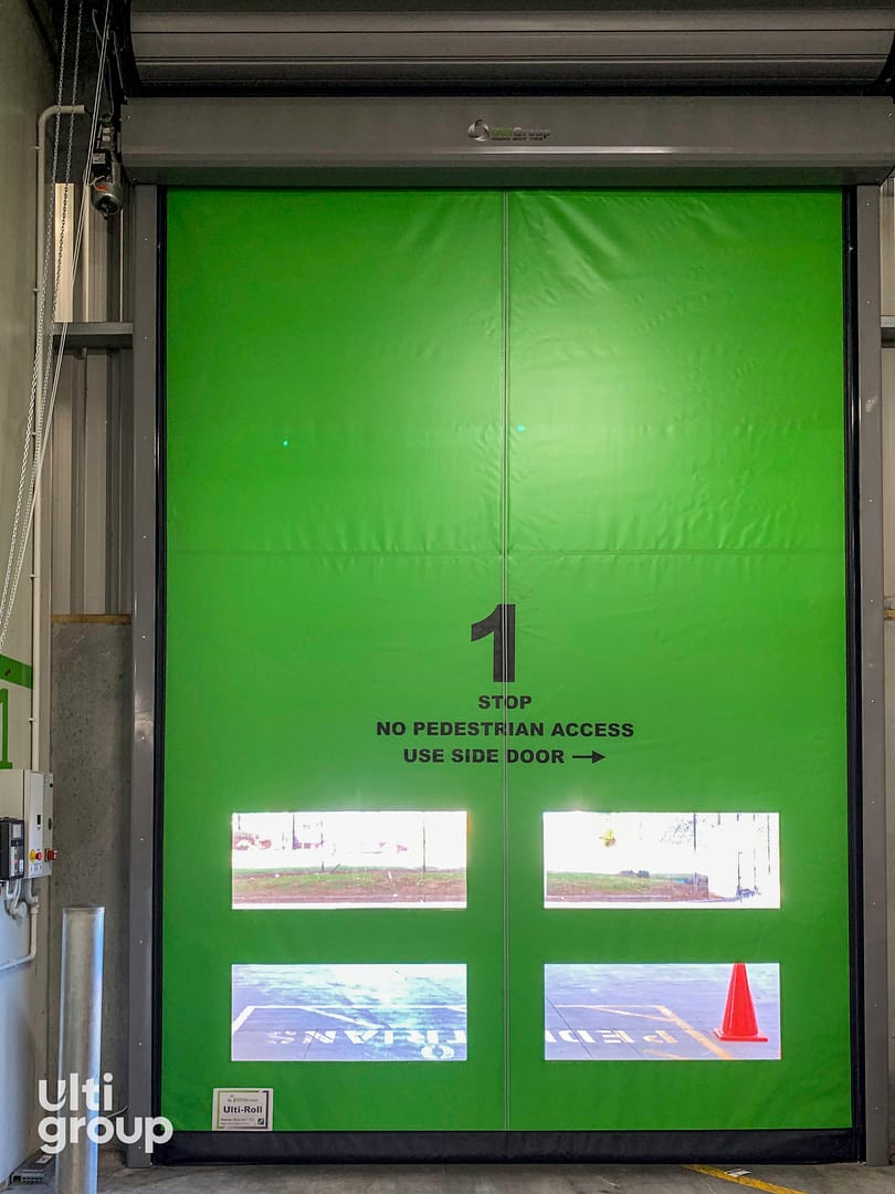 Green Ulti Komby Door with vision panels and safety signage.