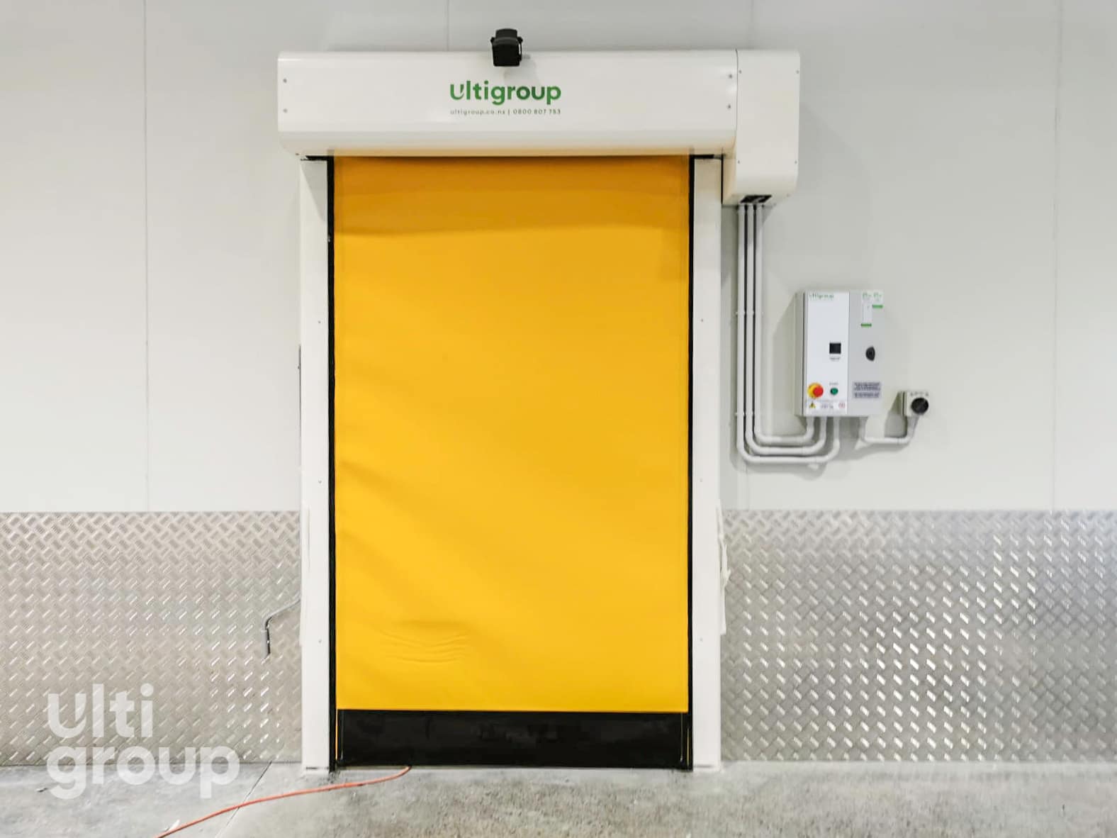 Yellow high speed roll door installed in a warehouse with a white control box.