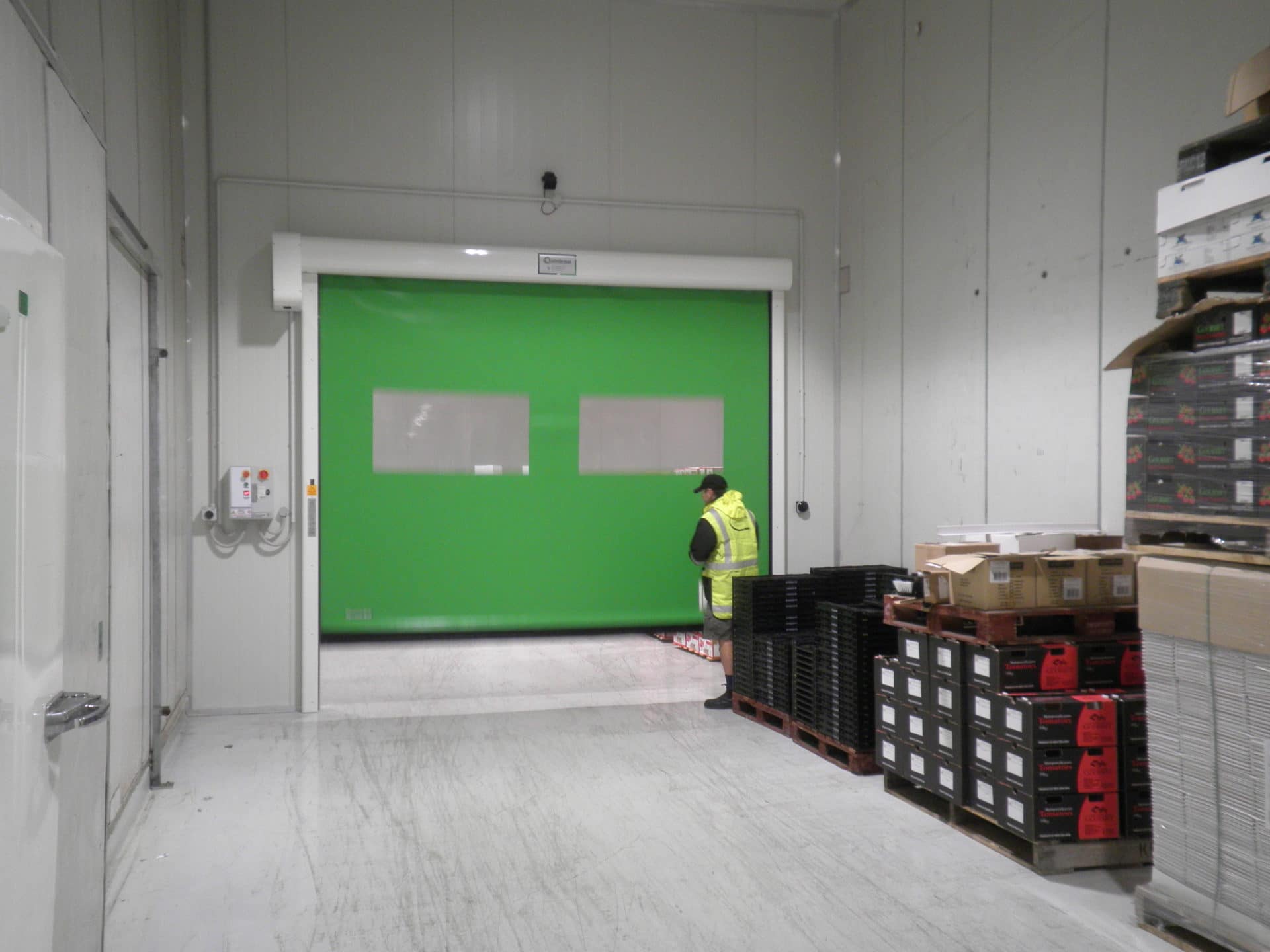 Green rapid acting door with clear vision panels in a warehouse