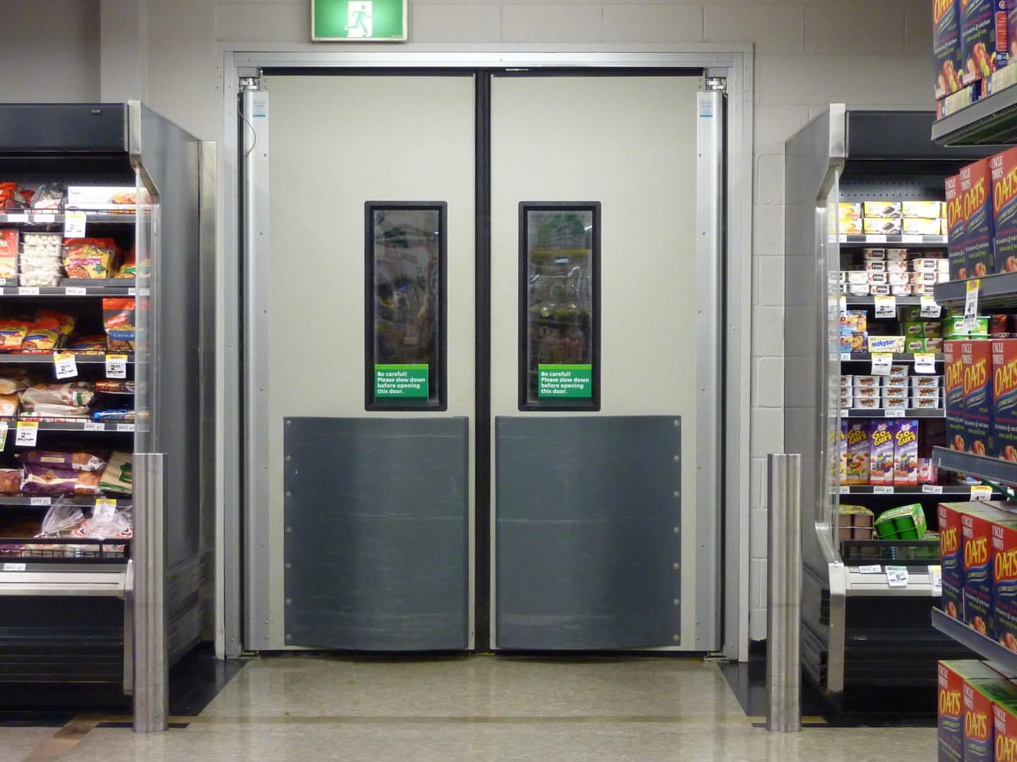 Ulti 4500 Series double swing doors with vision panels in a retail supermarket aisle.