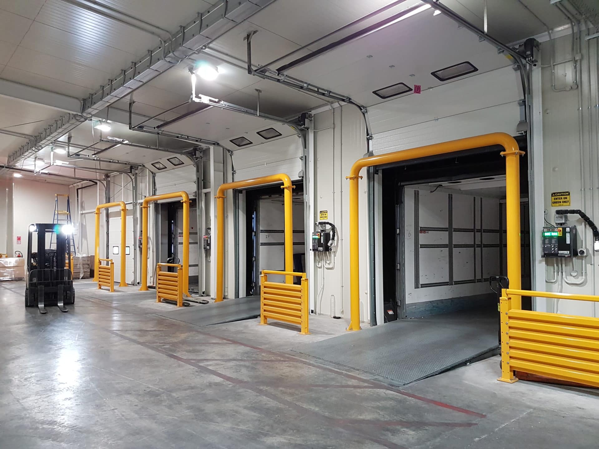 Row of loading docks with Vertical Storing Dock Levellers and yellow safety barriers.