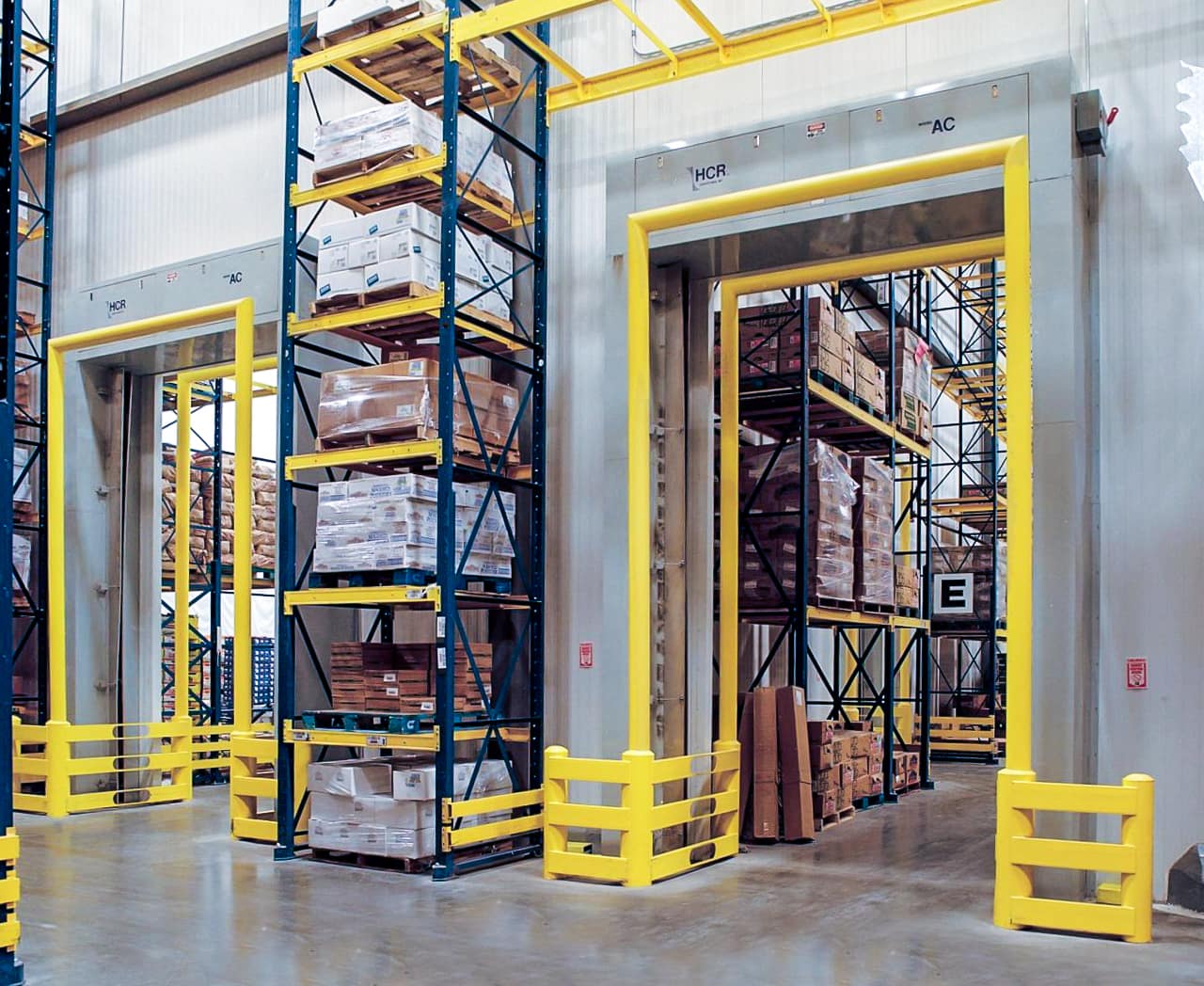 Industrial air curtain system installed over warehouse doorways with yellow safety barriers.