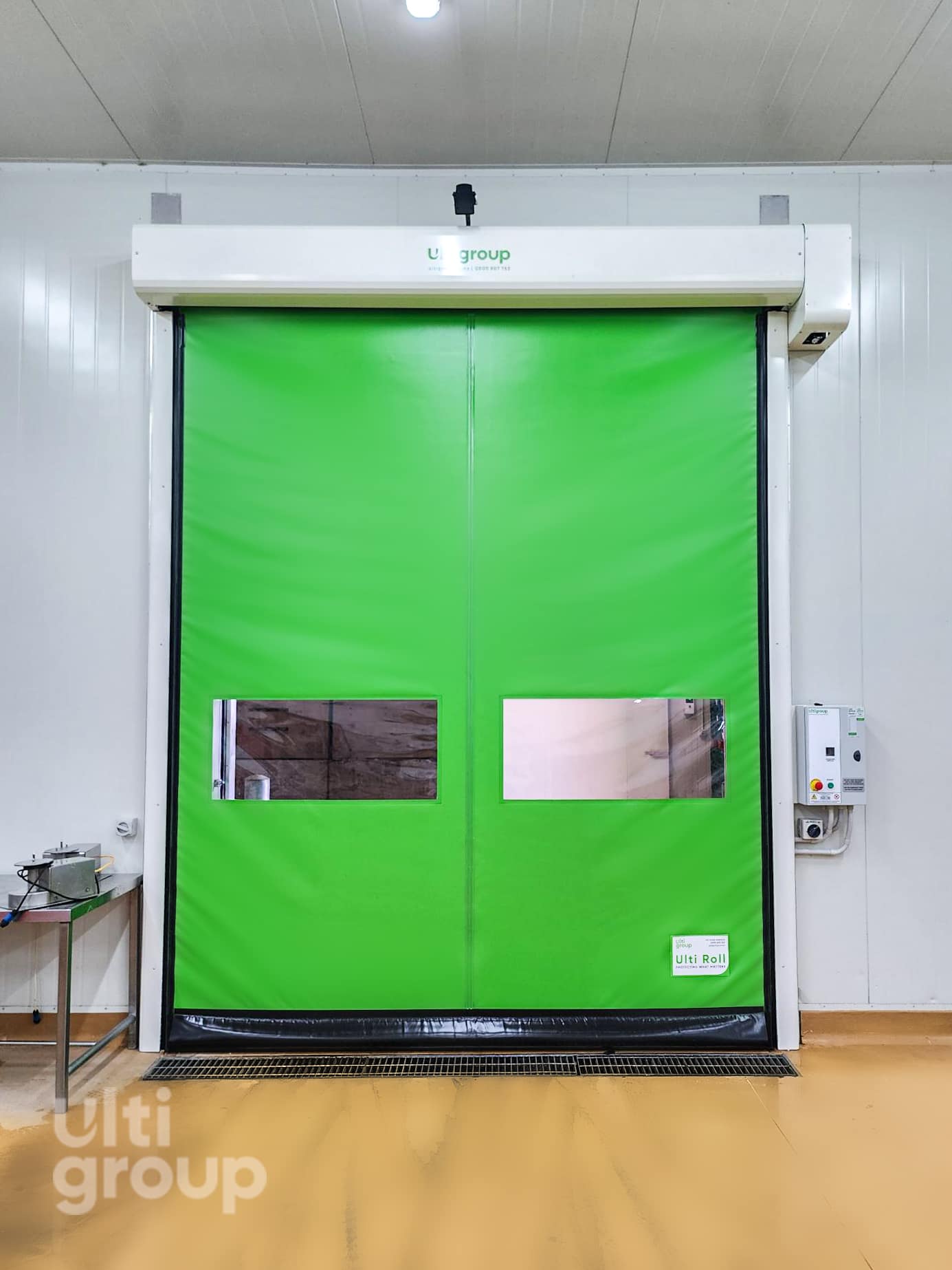 Green Ulti Roll high speed door with vision panels in a warehouse facility.