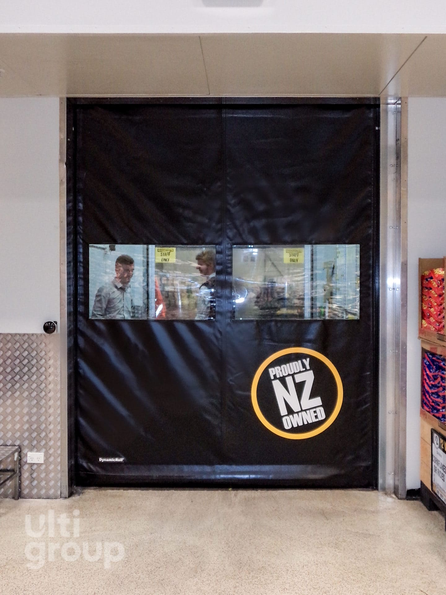 Black Ulti-Roll rapid door with vision panels and Proudly NZ Owned logo.