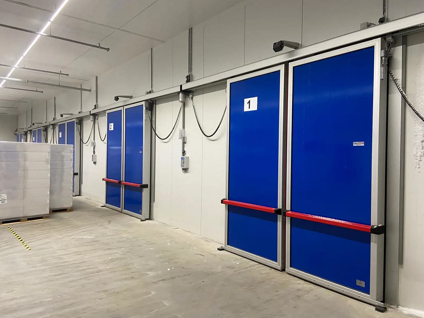 Blue insulated bi-parting sliding doors in a cold storage facility.