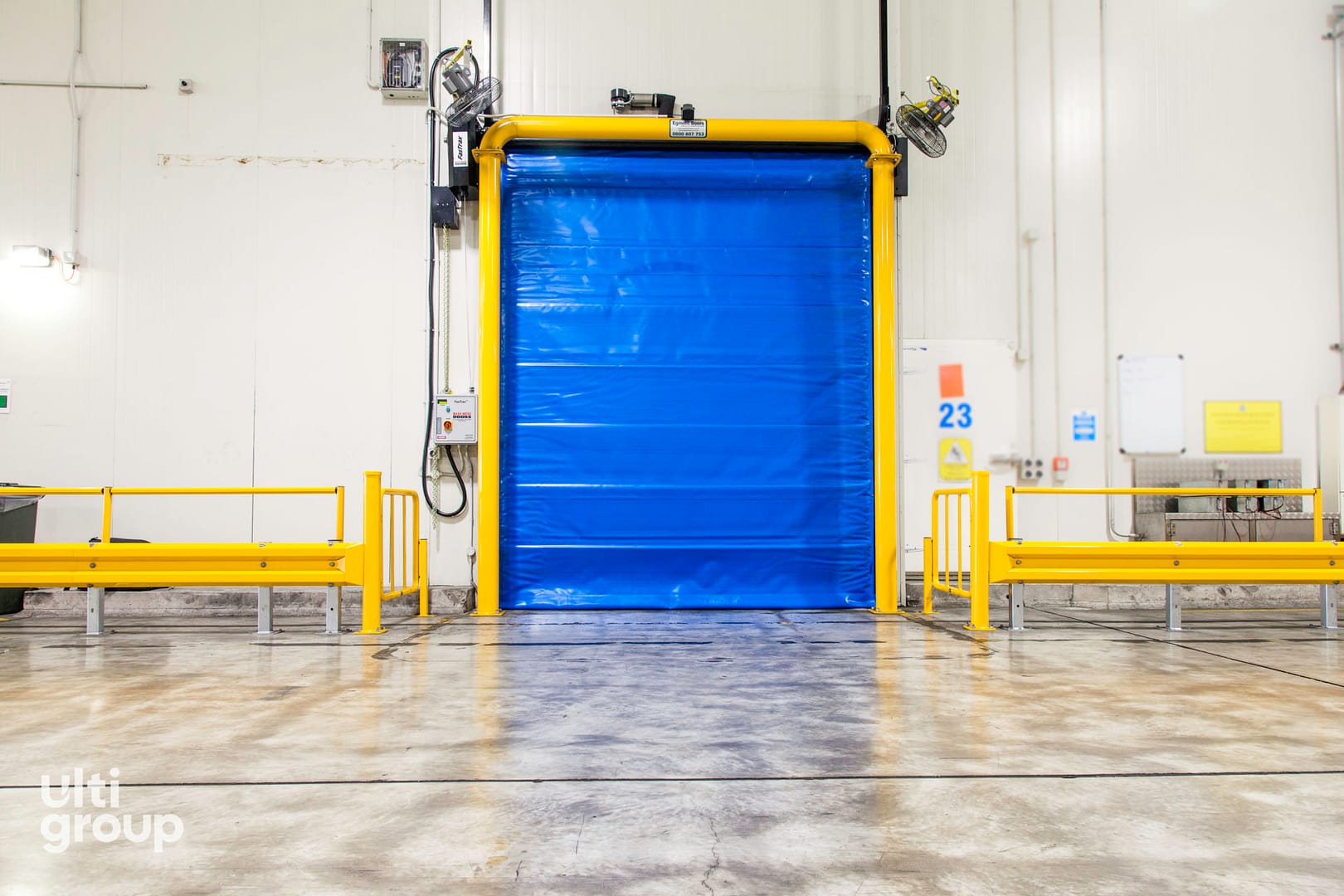Blue Fastrax FR Door installed in a facility with yellow safety barriers.