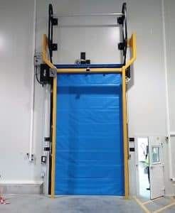 Blue high-speed industrial door installed next to a white personnel door.