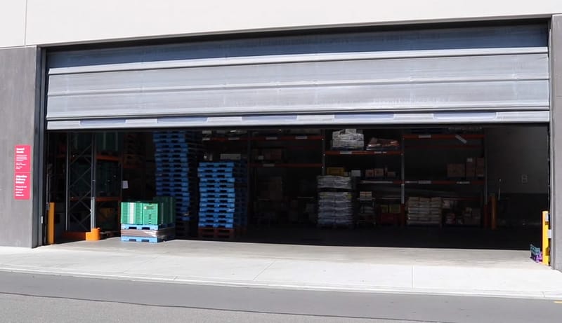 Large opening span industrial door partially open at a warehouse entrance.