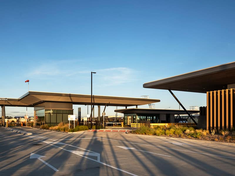 Modern industrial facility entrance with flat-roofed canopies and security gatehouses.