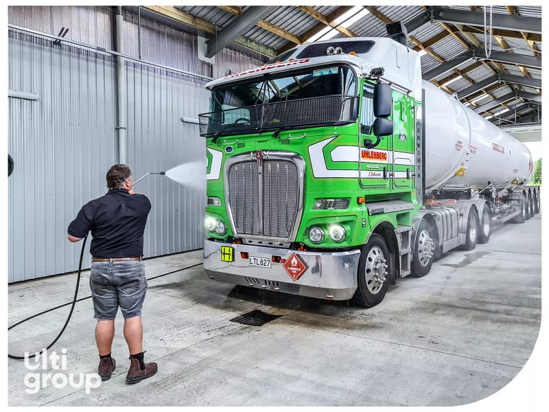 Green Uhlenberg Haulage truck being washed inside a facility featuring Ulti Group sectional doors.