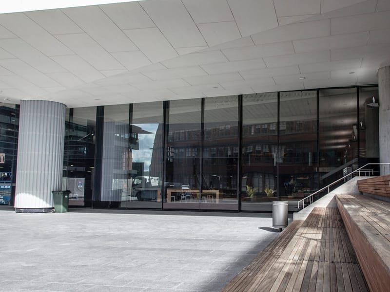 Large glass facade and outdoor wooden seating area at a modern facility.