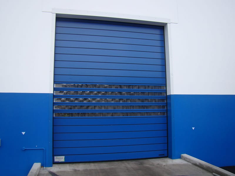 Blue Ulti Spiral Door installed in a white and blue industrial building exterior.