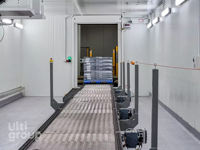 Pallet on a conveyor system moving through an automated industrial doorway.