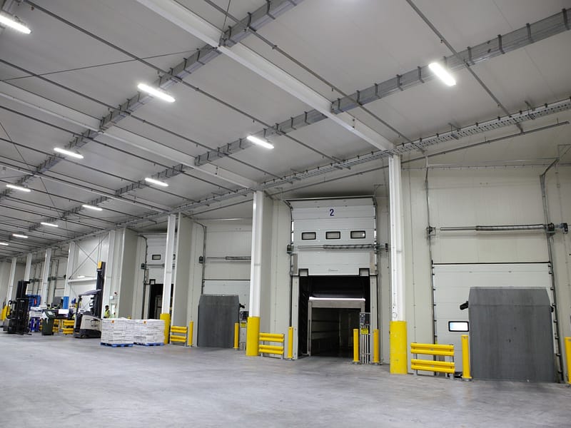 Vertical Storing Dock Levellers and sectional doors in a warehouse loading bay.