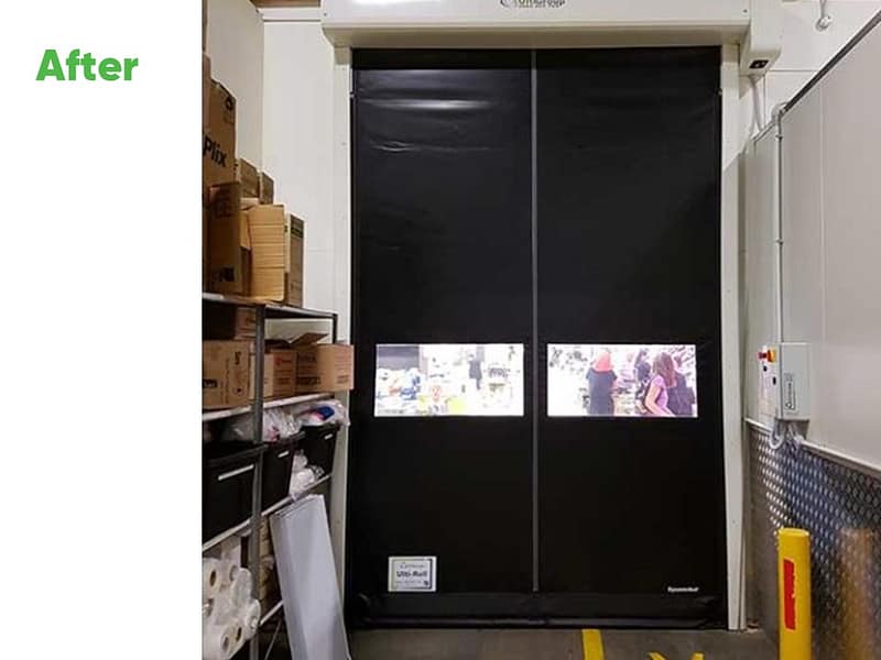Black Ulti-Roll high speed door with clear vision panels in a warehouse.
