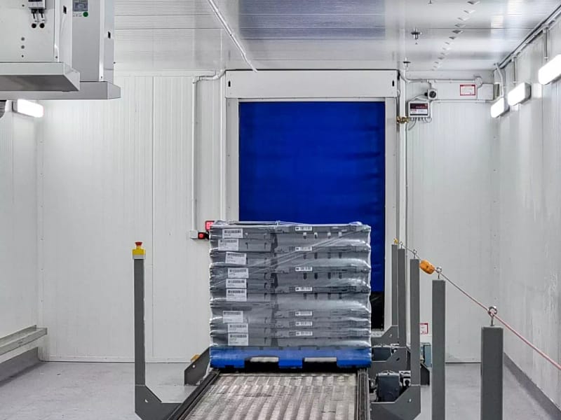 A pallet of goods on a conveyor system moving towards a blue Ulti Roll door.